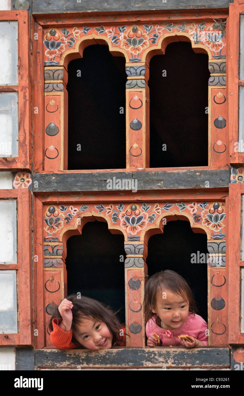 Kinder betrachten Trongsa aus einem Haus mit traditionellen bhutanesischen verzierten Fenstern. Stockfoto