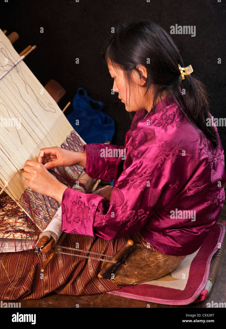 Eine Frau spinnt ein kompliziertes Muster in Seide auf ihre traditionellen hölzernen Webstuhl. Stockfoto