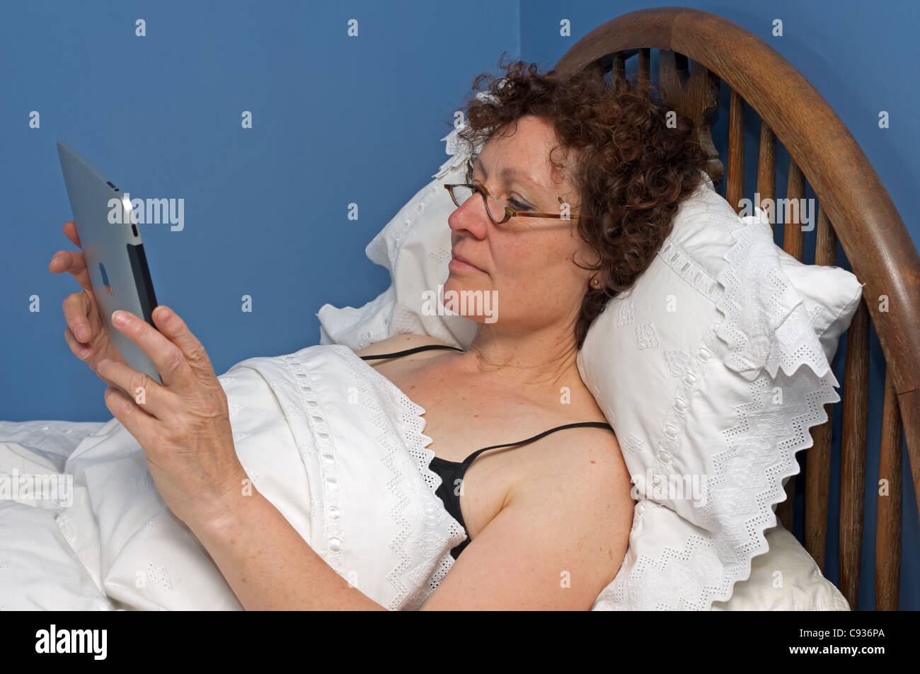 Frau im Bett und las ein elektronisches Buch Stockfoto