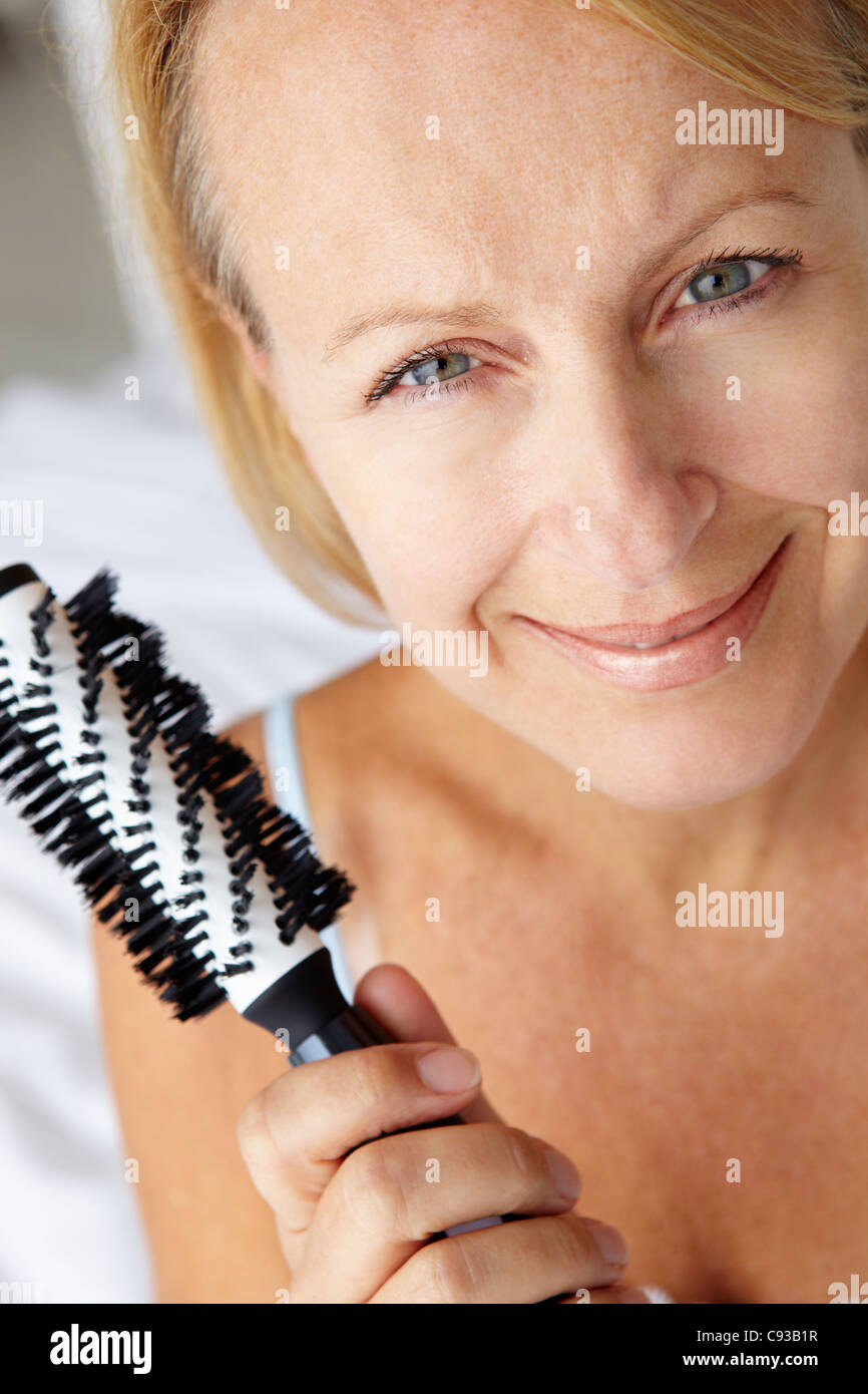 Mitte Alter Frau mit Haarbürste Stockfoto