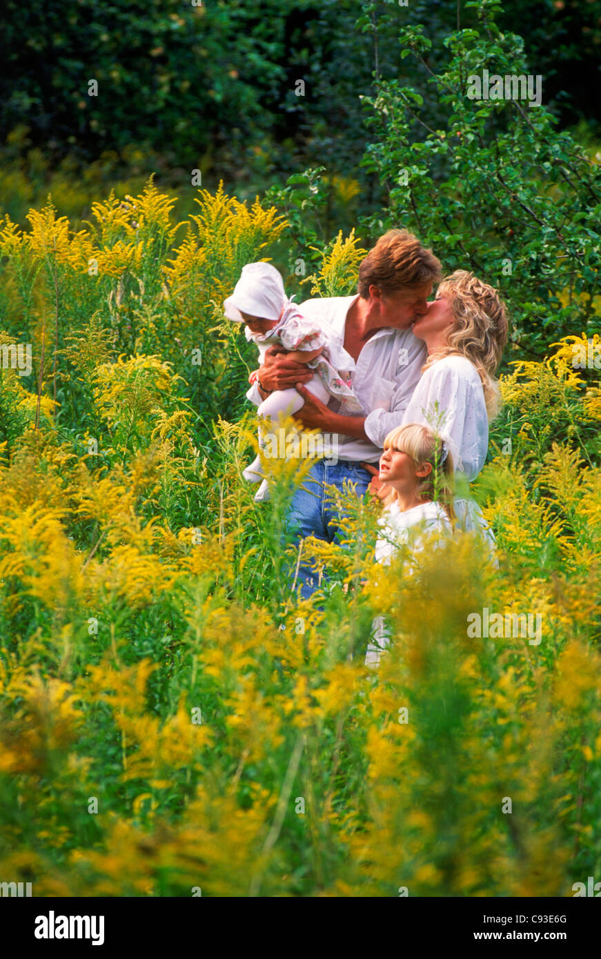 Vierköpfige Familie im Gebiet der wilden gelben Blüten in Schweden Stockfoto