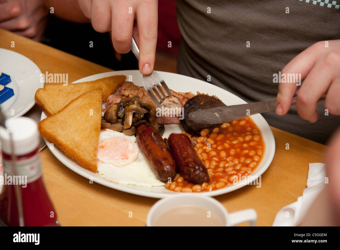 Ein "Greasy Spoon" gebraten englisches Frühstück - Speck, Ei, Würstchen, Bohnen, geröstetes Brot, Blutwurst - in einem Café UK Stockfoto