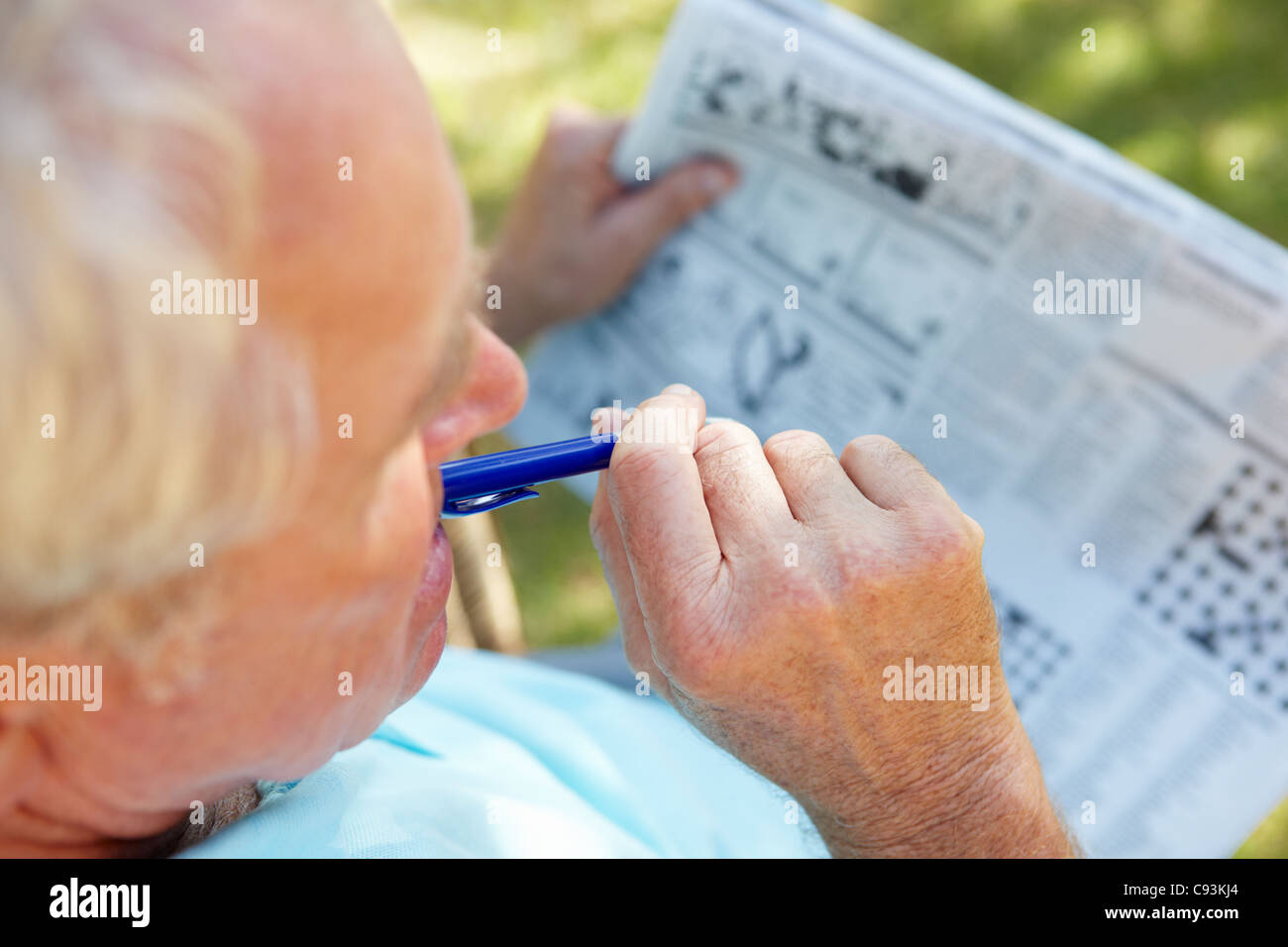 Ältere Mann tut Kreuzworträtsel im freien Stockfoto