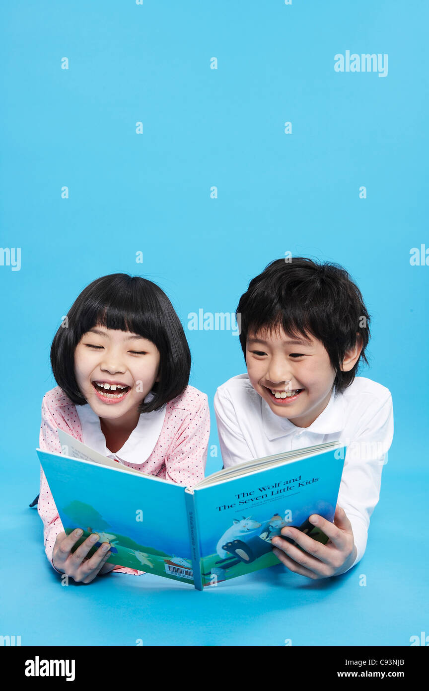 Jungen und Mädchen liegend Buch zu lesen, Lächeln Stockfoto