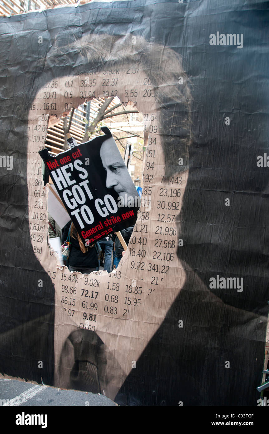 Ein Demonstrant hält eine Foto von Cameron auf ein Plakat mit einem Schild mit der Aufschrift, dass er hat zu gehen, durch eine Montage von ihm und Figuren gesehen Stockfoto
