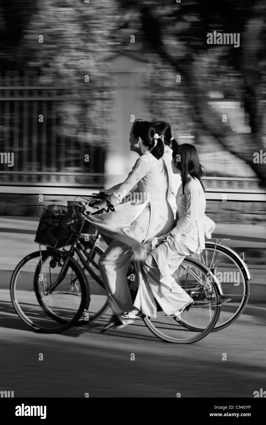 Asien, Vietnam, Hue. Mädchen in traditionellen vietnamesischen weißen Kleidern auf dem Fahrrad von der Schule zurück. Stockfoto