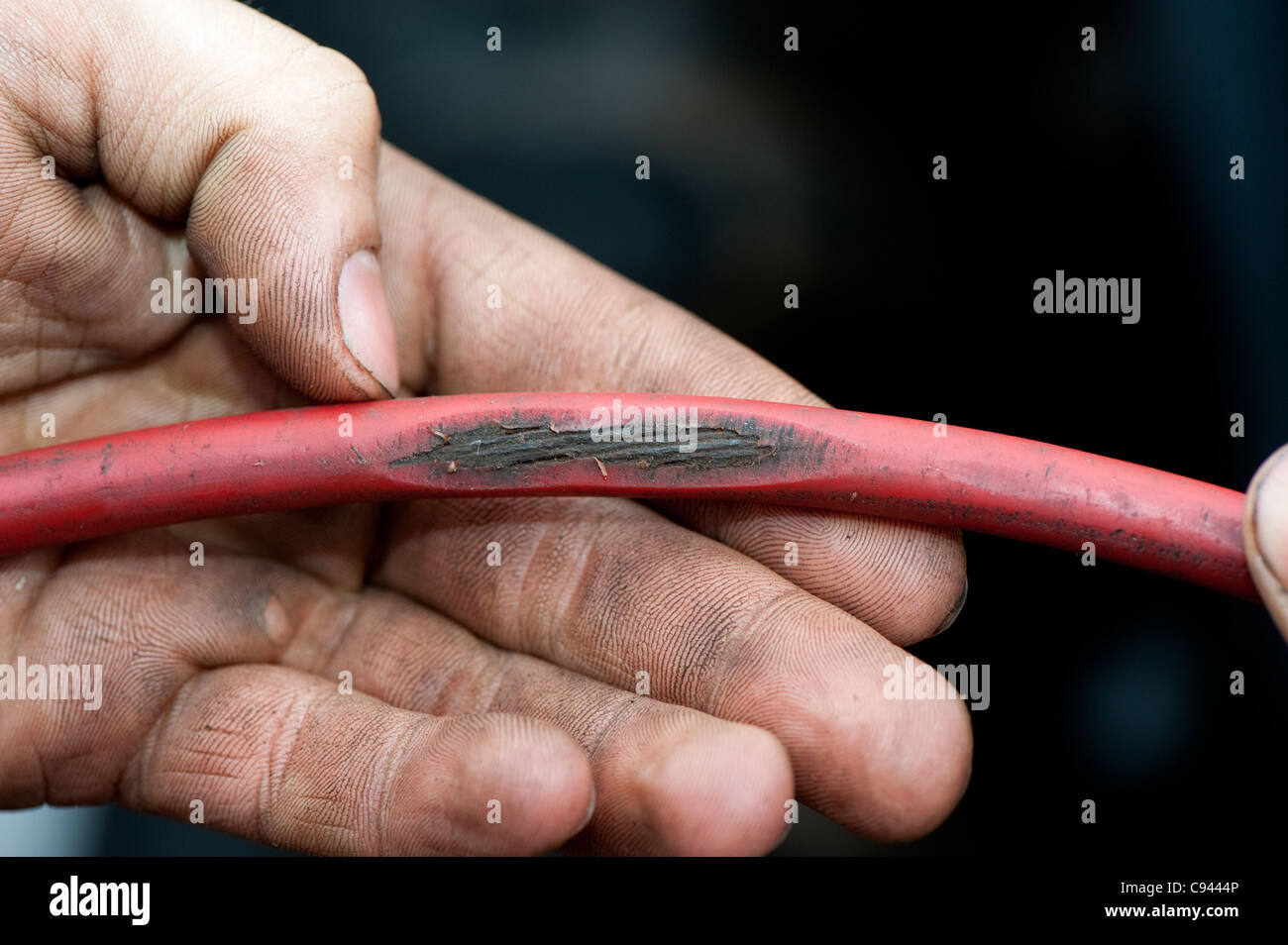 Mechaniker mit abgenutzten Kabel, das könnte gefährlich sein Stockfoto