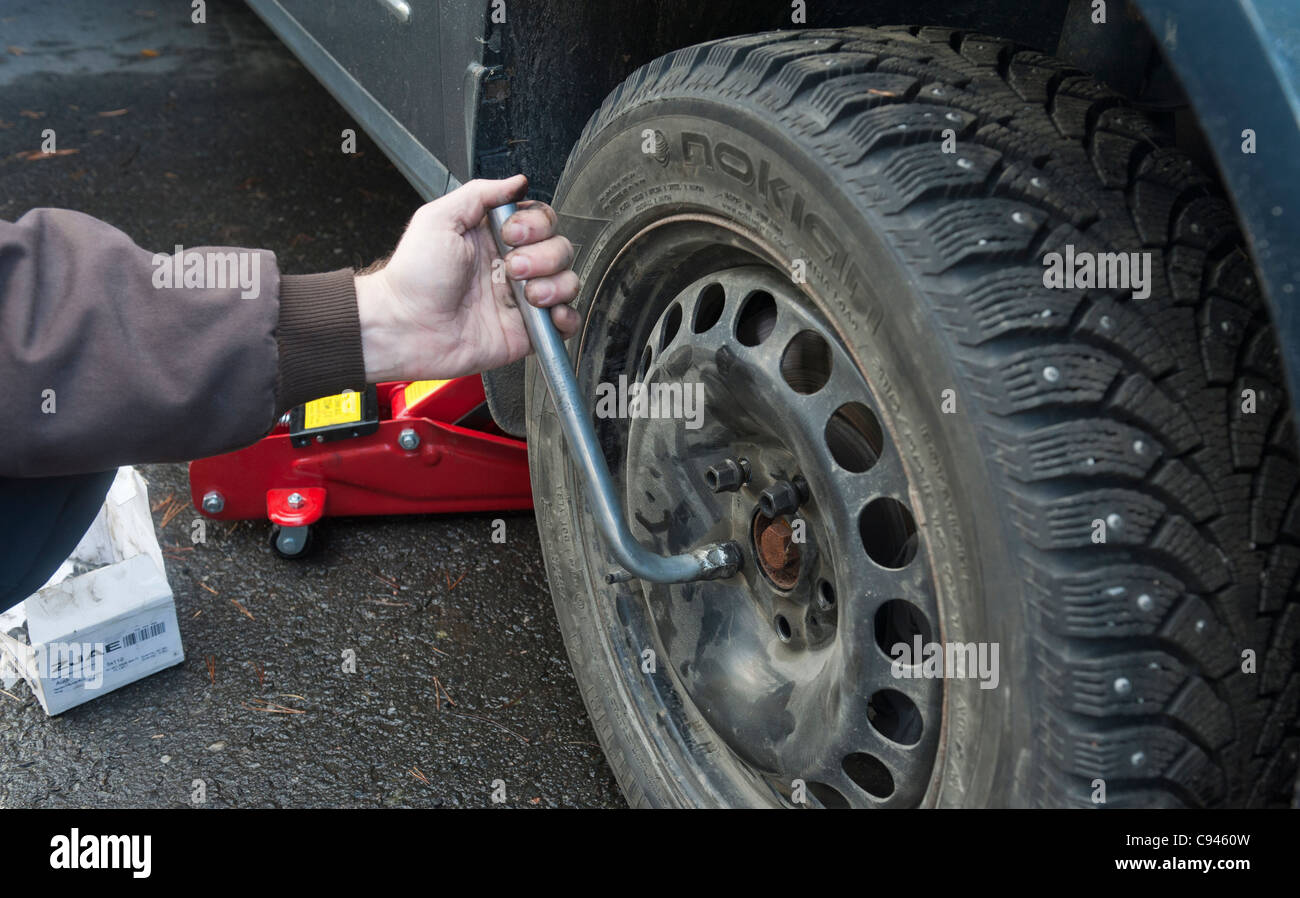 Ein Mann verändert die Sommerreifen, Winterreifen, Antizipation des finnischen Winters. Stockfoto