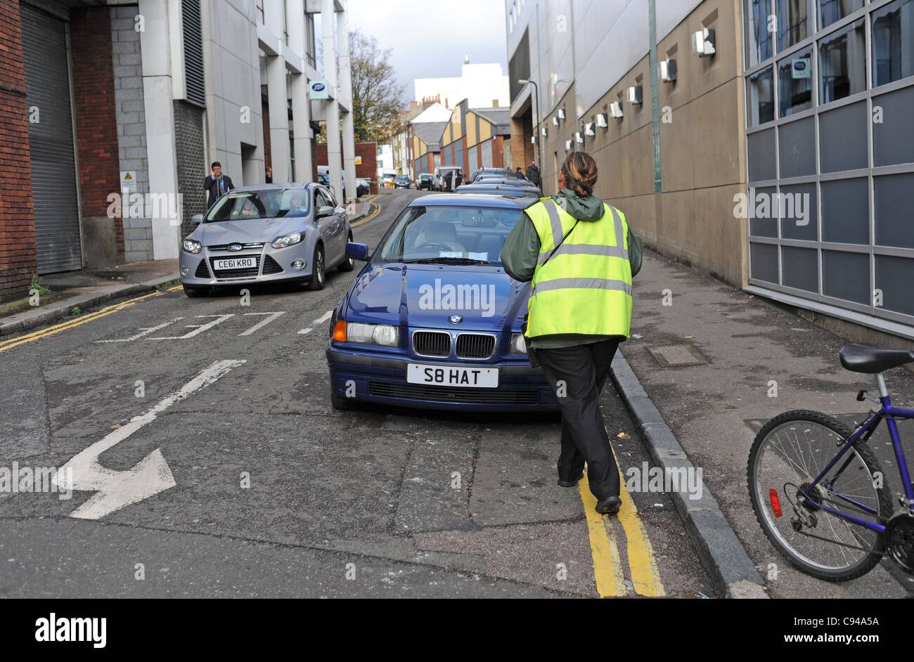 Weibliche Traffic Warden, ein Auto geben ein Ticket für das Parken auf doppelte gelbe Linien Brighton UK Stockfoto