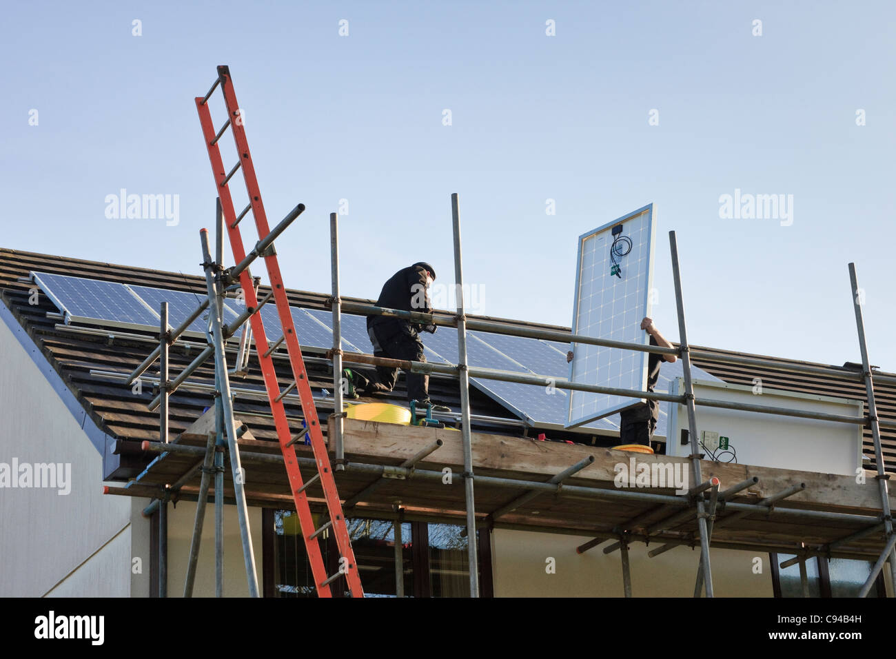UK, Großbritannien. Arbeiter, die passende neue Sonnenkollektoren auf einem Hausdach für die Regelung der Einspeisevergütung Stockfoto