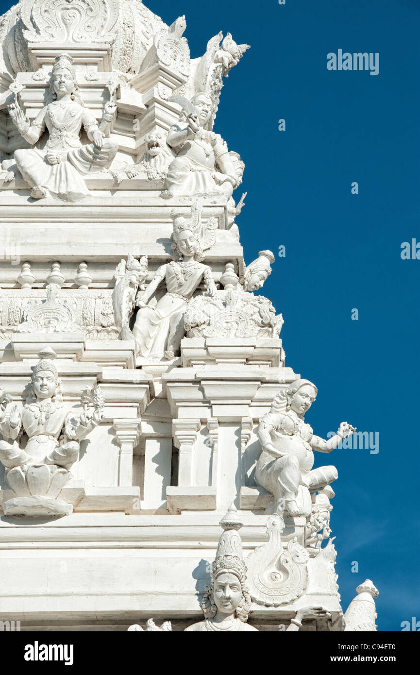 Weiße Hindutempel dekoriert mit Gottheiten vor blauem Himmel. Puttaparthi, Andhra Pradesh, Indien Stockfoto