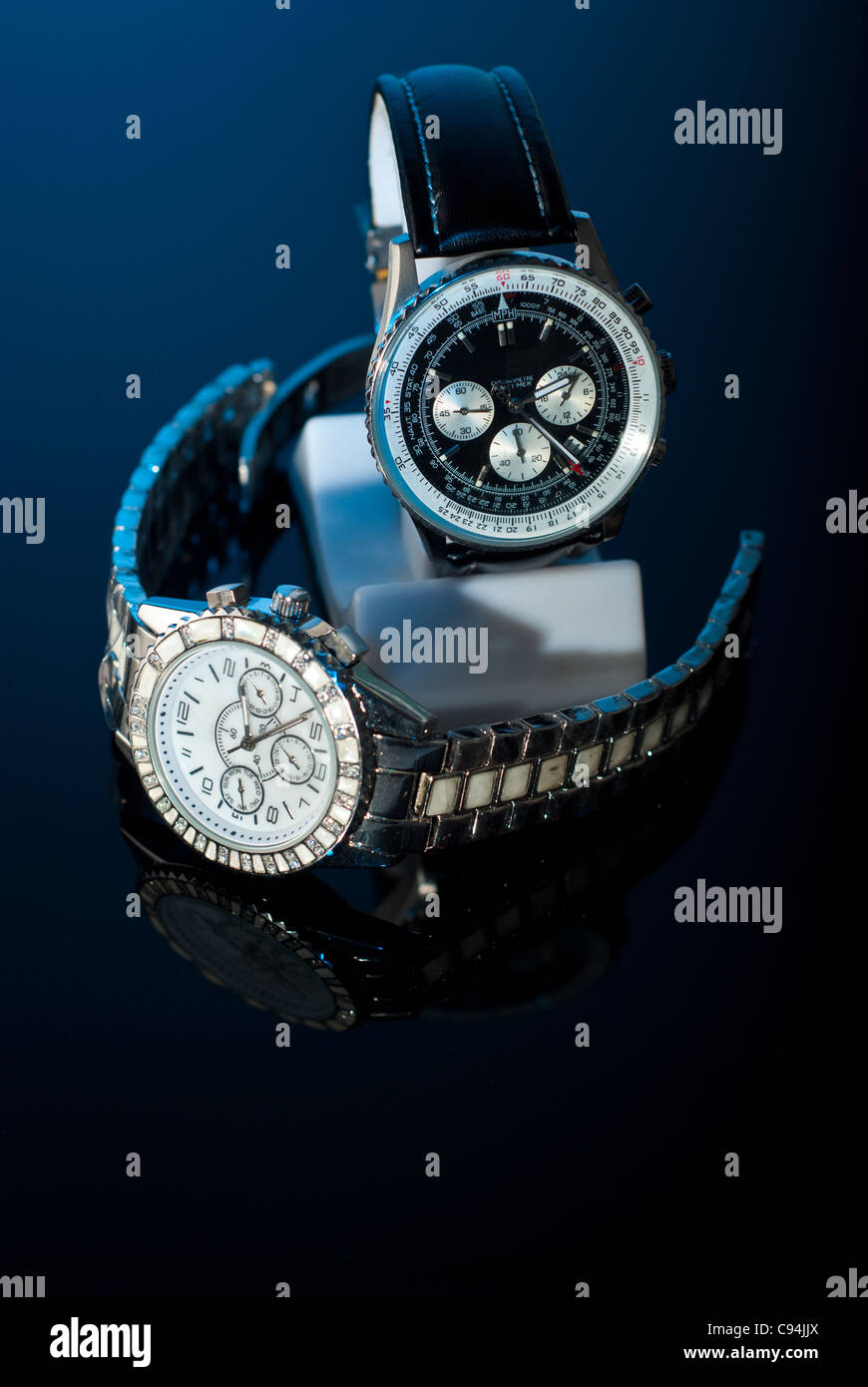 Zwei elegante Uhren für Womans und mans auf schwarzem Hintergrund mit blauem Licht Stockfoto
