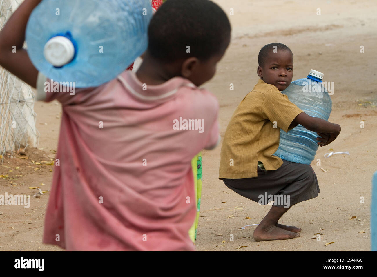 Kinder tragen Wasser von hinten aus einem Brunnen in Dar Es Salaam, Tansania, Ostafrika. Stockfoto