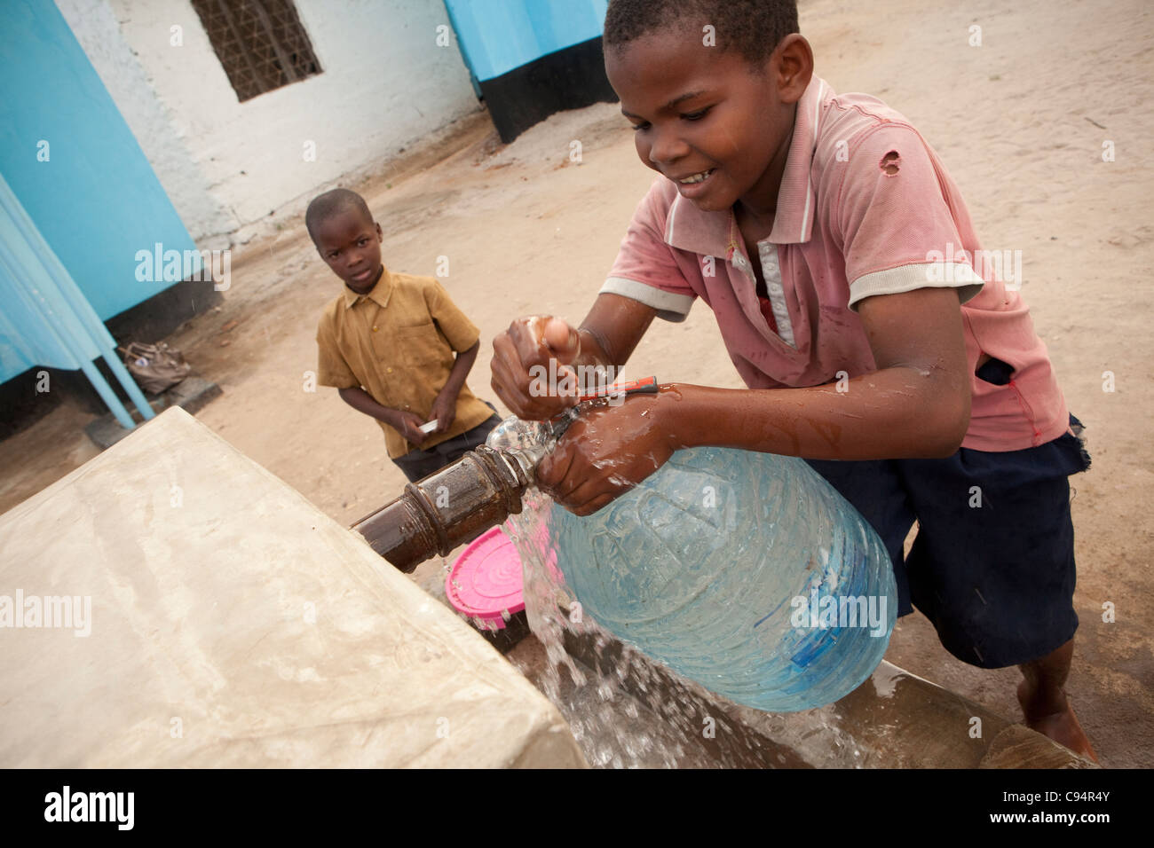 Ein Junge holt Wasser an einem Brunnen in Dar Es Salaam, Tansania, Ostafrika. Stockfoto