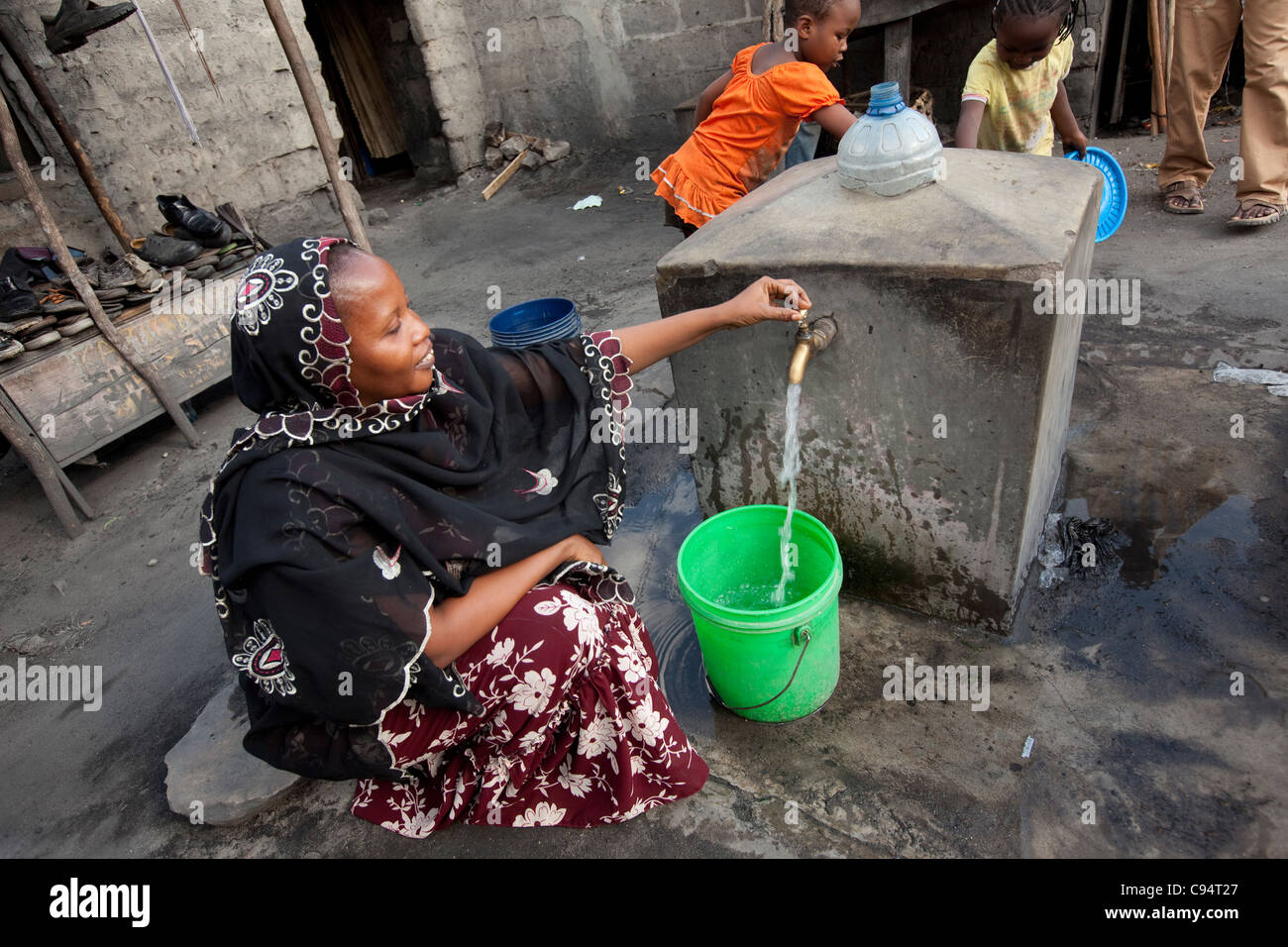 Einwohner von Temeke, einem Slum in Dar Es Salaam, Tansania, Ostafrika, sammeln Wasser aus einem Hahn der Gemeinschaft. Stockfoto