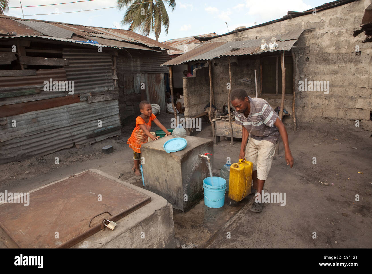Einwohner von Temeke, einem Slum in Dar Es Salaam, Tansania, Ostafrika, sammeln Wasser aus einem Hahn der Gemeinschaft. Stockfoto