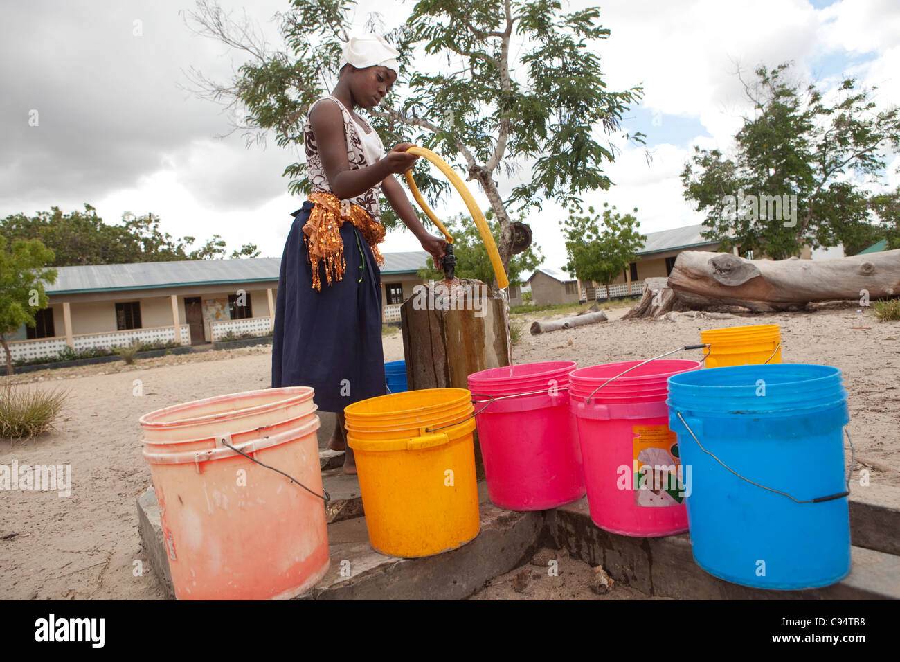 Eine junge Frau füllt Eimer Wasser in einer Gemeinschaft außerhalb Dar Es Salaam, Tansania, Ostafrika. Stockfoto