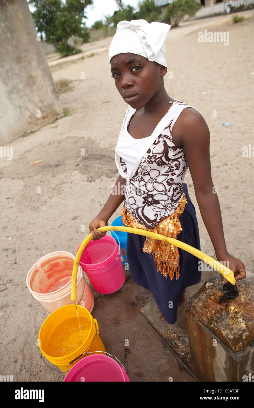 Eine junge Frau füllt Eimer Wasser in einer Gemeinschaft außerhalb Dar Es Salaam, Tansania, Ostafrika. Stockfoto