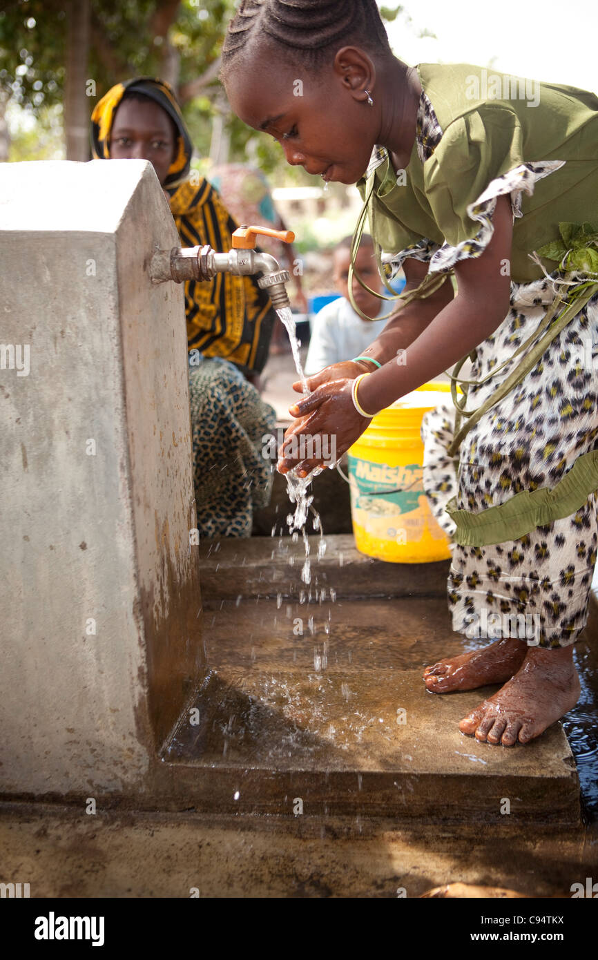 Ein Kind wäscht ihre Hände in einer Gemeinschaft gut in Dar Es Salaam, Tansania, Ostafrika. Stockfoto