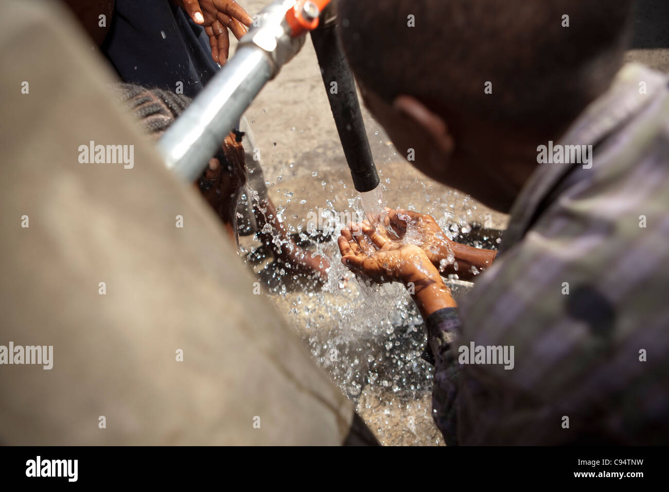 Kinder trinken Wasser aus einem Bohrloch in Dar Es Salaam, Tansania, Ostafrika. Stockfoto