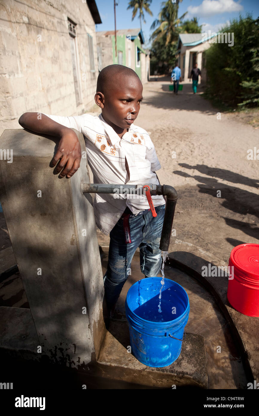 Ein Junge holt Wasser an einem Brunnen in Dar Es Salaam, Tansania, Ostafrika. Stockfoto