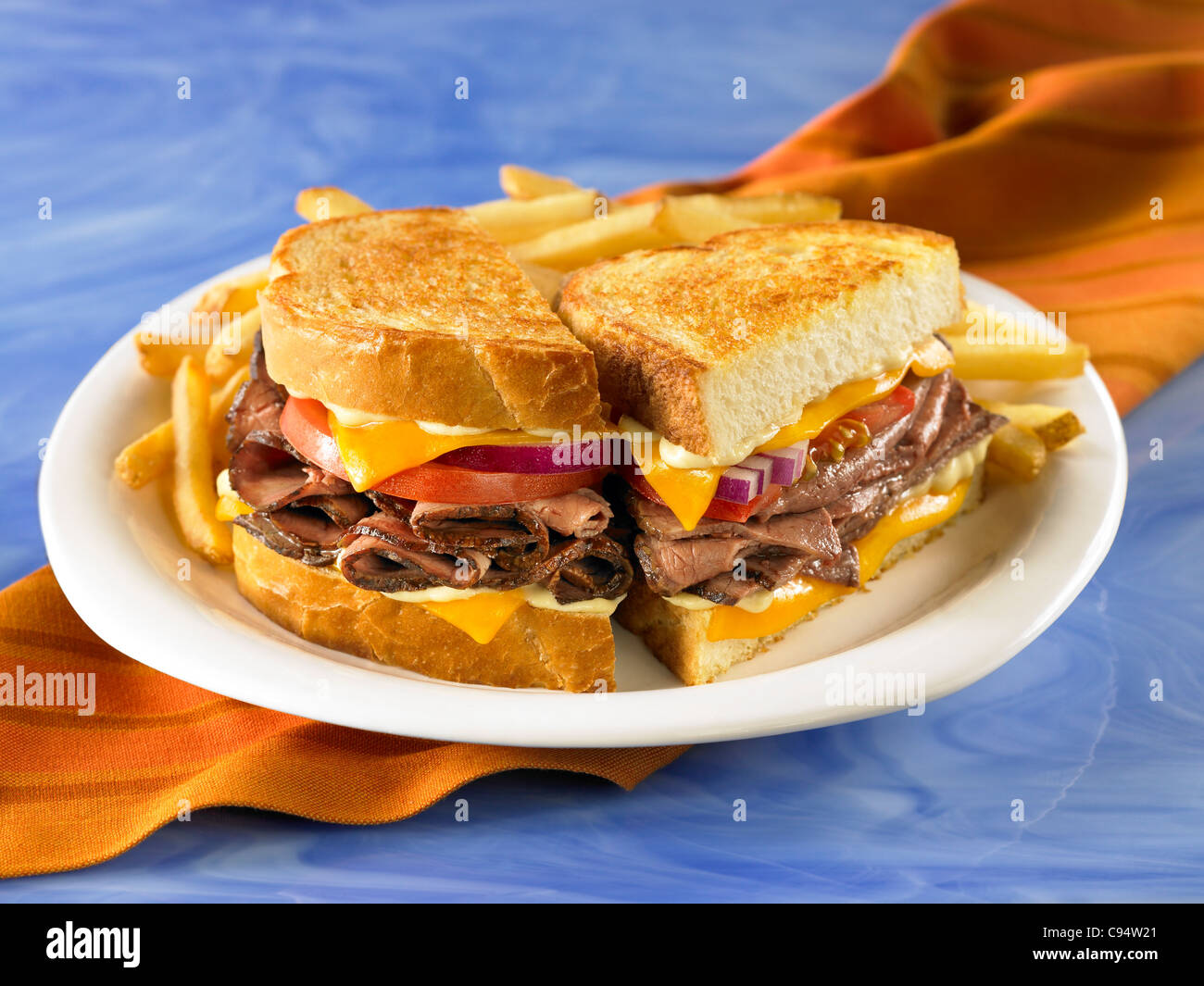 Roast Beef Sandwich mit Tomaten und Käse auf gegrilltem Sauerteigbrot mit Pommes frites Stockfoto
