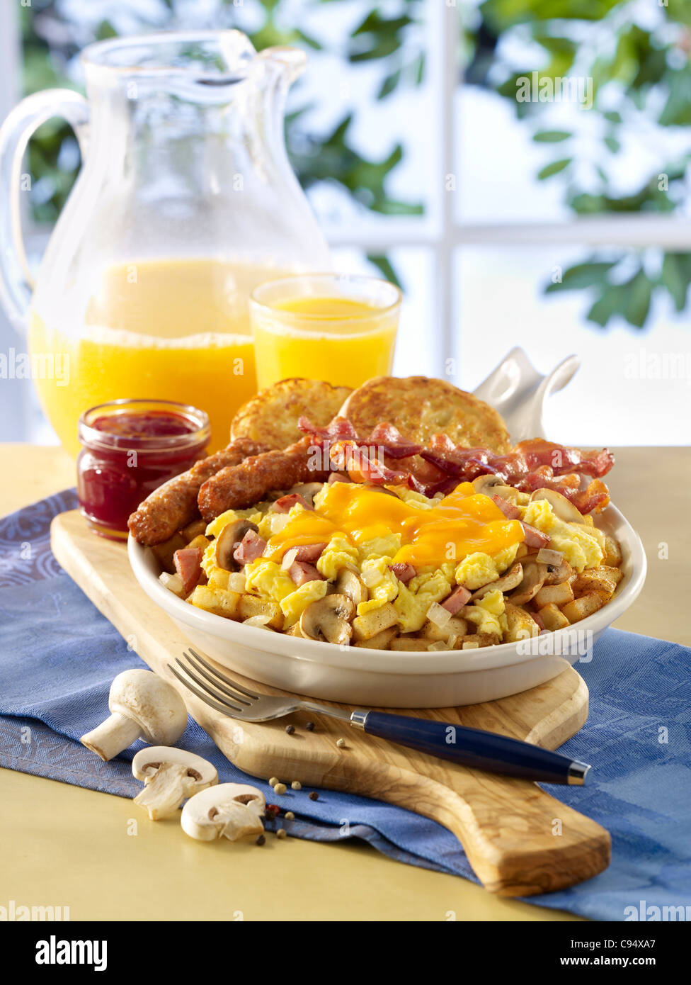 Rührei Ei und Schinken Pfanne Frühstück mit Wurst, Speck, Toast und Orangensaft Stockfoto