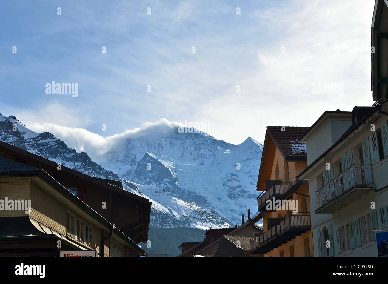 Eine Wolke Cloud fließt vom Gipfel des Berges Jungfrau über den Dächern des Dorfes in Wengen. Stockfoto