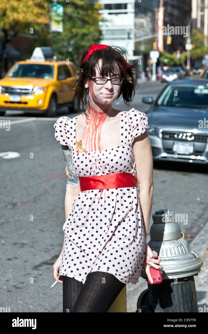 Transvestit mit Zigarette stützte sich auf Hydranten in Polka Dot Kleid gefälschte Busen & Kunstblut New York für Halloween gekleidet. Stockfoto