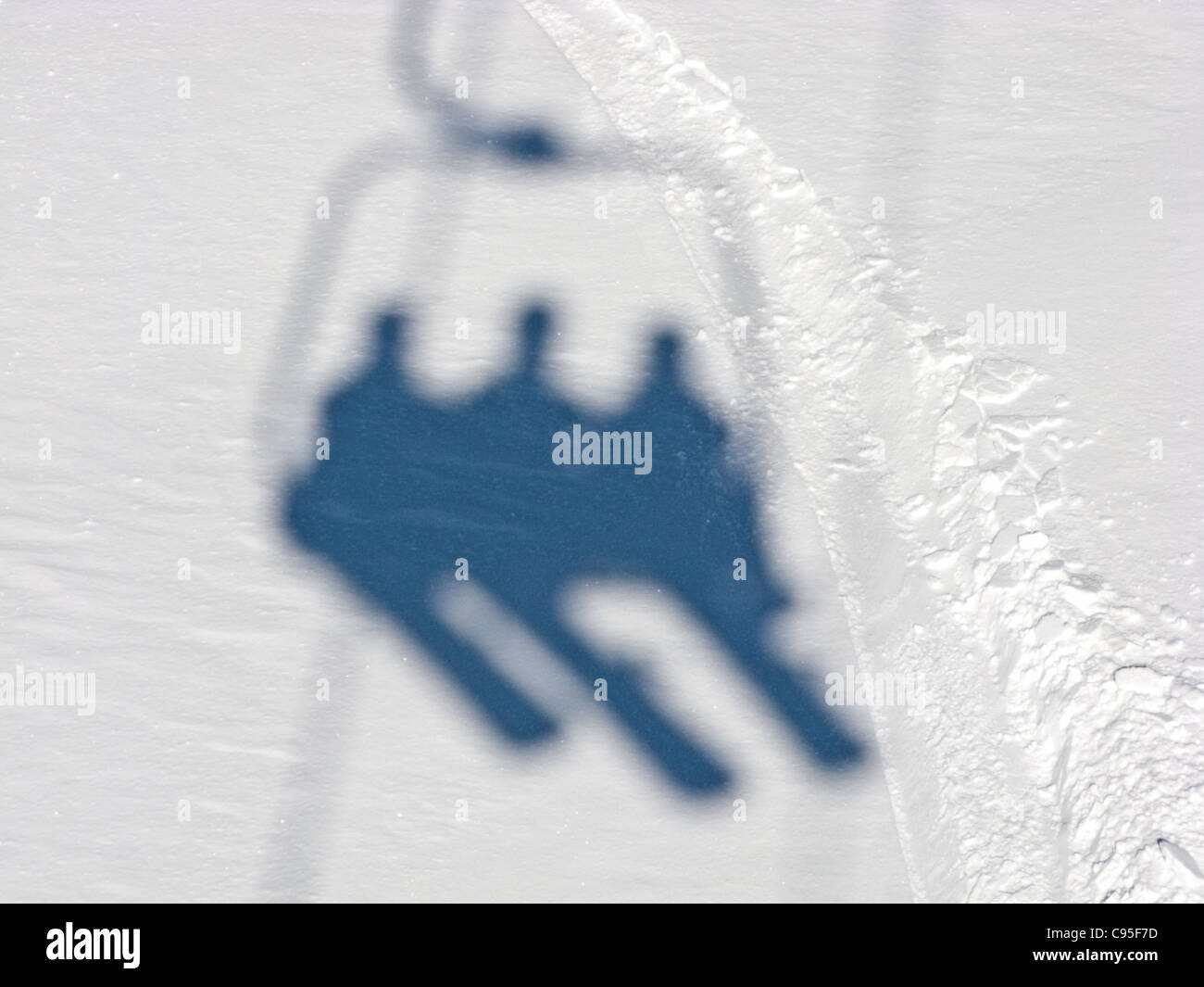 Schatten der drei Snowboarder sitzend auf dem Sessellift Stockfoto