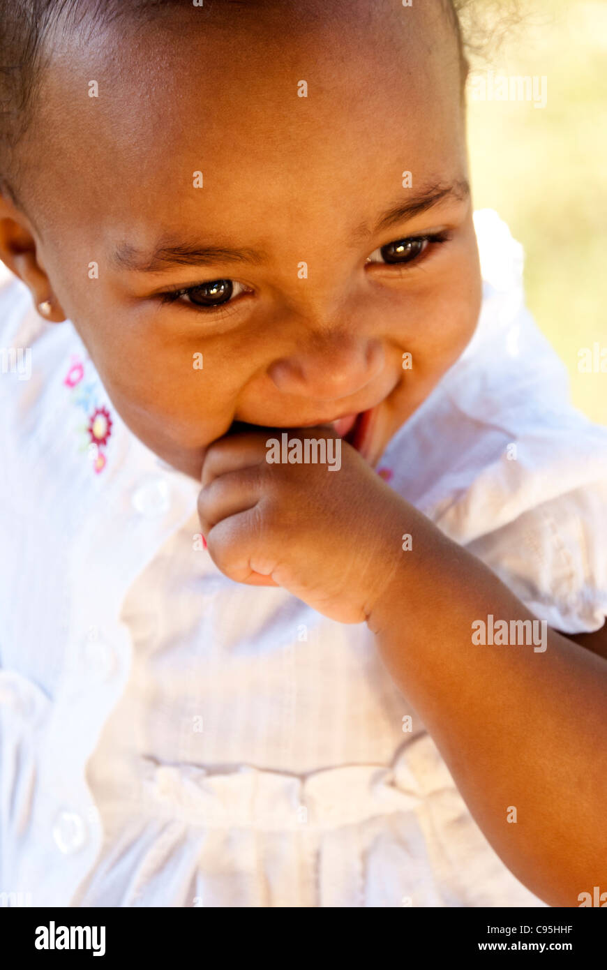 Fröhliches afroamerikanische Mädchen lächelnd mit Finger in den Mund Stockfoto
