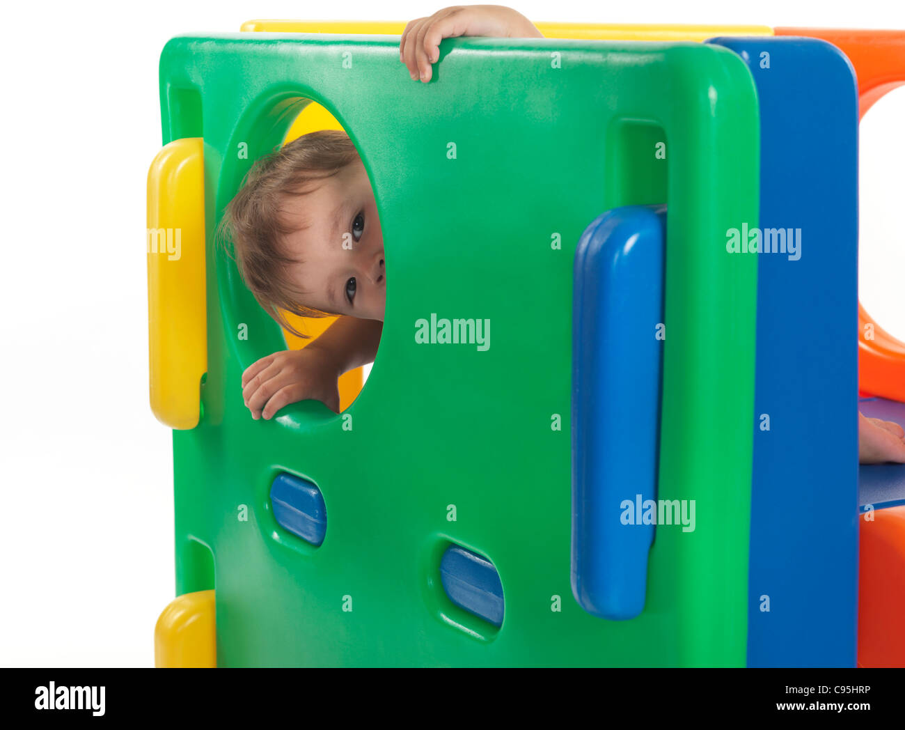 Ein und eine Hälfte Jahr alt Kind aus einem runden Fenster in einem Kletterer Spielzeug suchen. Isoliert auf weißem Hintergrund. Stockfoto