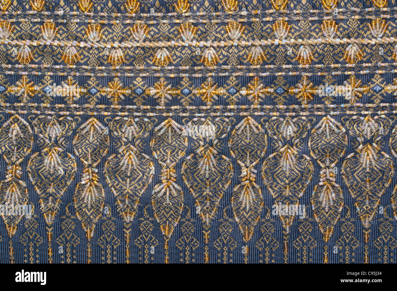 Ein Detailbild der blauen und gelben Blumenmuster in Thai Seide Stoff mit Gewinde und Perlen Stockfoto