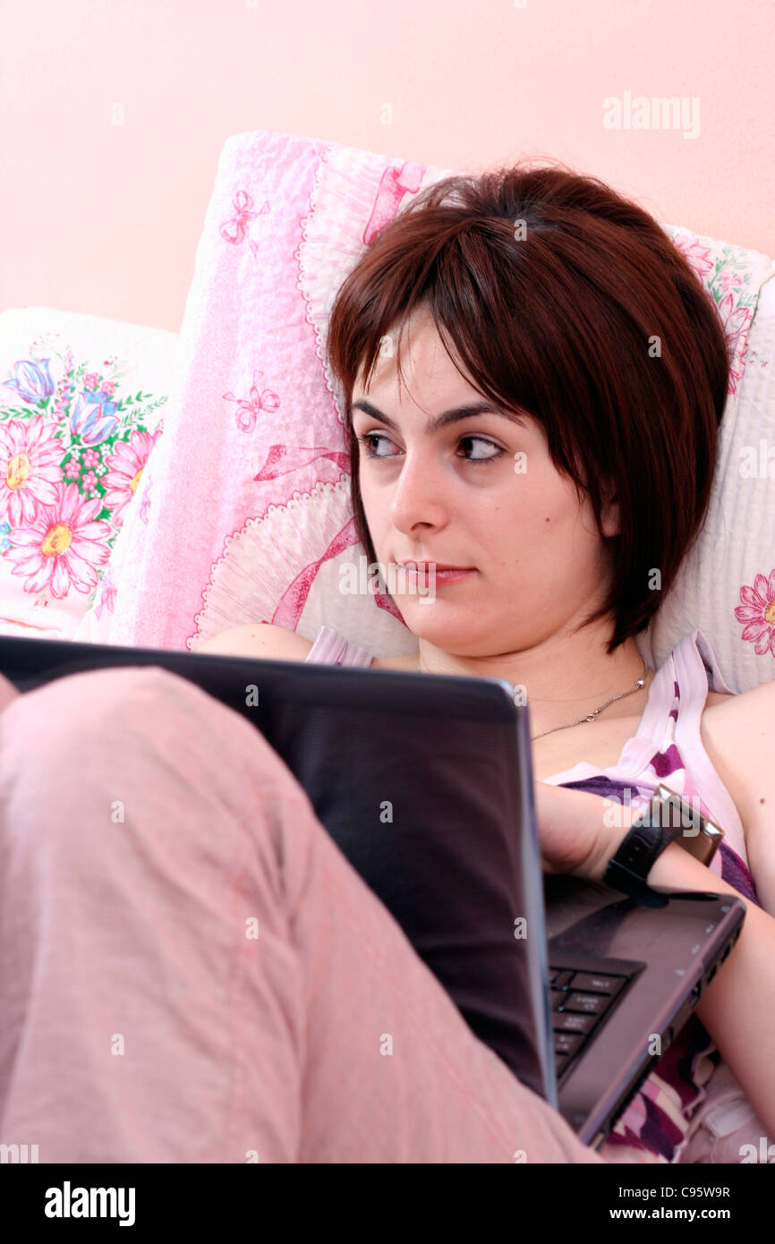 Junge Frau mit Laptop im Bett. Stockfoto