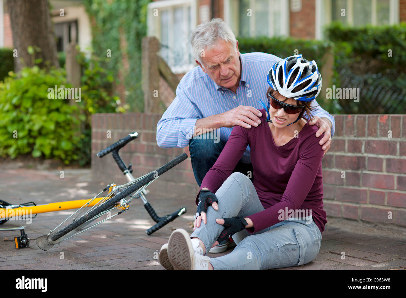 Fahrradunfall. Menschen helfen, einen Radfahrer, der vom Fahrrad gefallen ist. Stockfoto