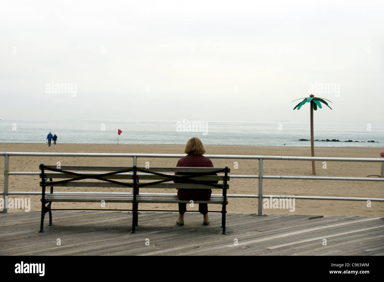 Eine einsame Frau sitzt auf einer Bank auf der Promenade, Brighton Beach, New York CIty, New York, USA. (c) Marc Jackson Stockfoto