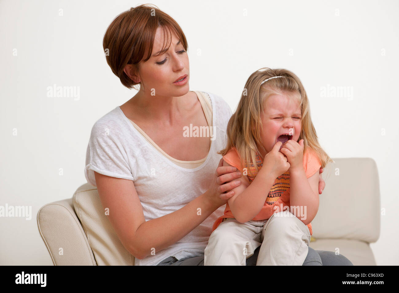 Kleinkind weint auf der Mutter Schoß. Stockfoto