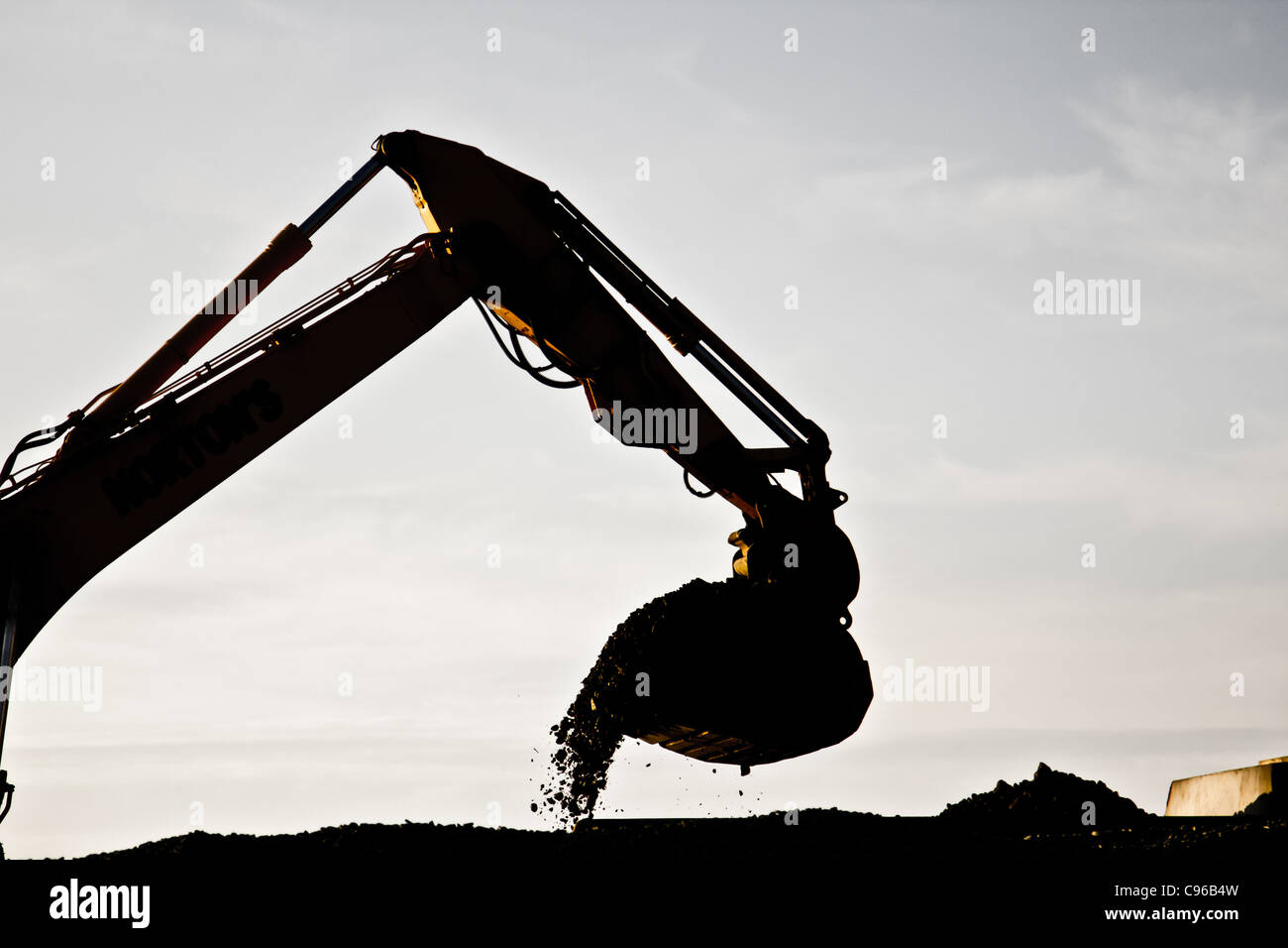 Silhouette eines mechanischen Bagger Arm und Eimer in der Abenddämmerung Gebäude Meer Verteidigung am Borth, Mitte Wales Stockfoto
