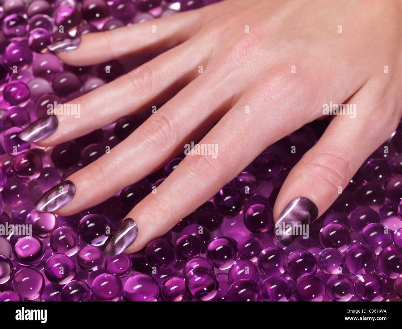 Lizenz erhältlich unter MaximImages.com Großaufnahme der Frauenhand mit Acrylnägeln und violettem nagellack Stockfoto