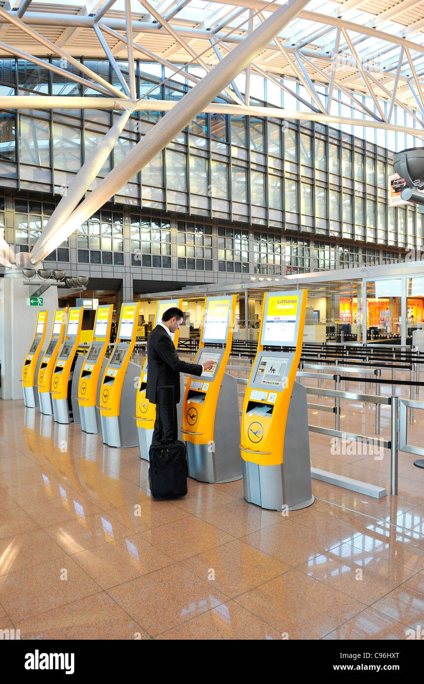 Junge, selbstbewusste Geschäftsmann, Reise trägt einen Anzug und Wandern mit Gepäck für ein Unternehmen am Flughafen, Hamburg, Deutschland Stockfoto