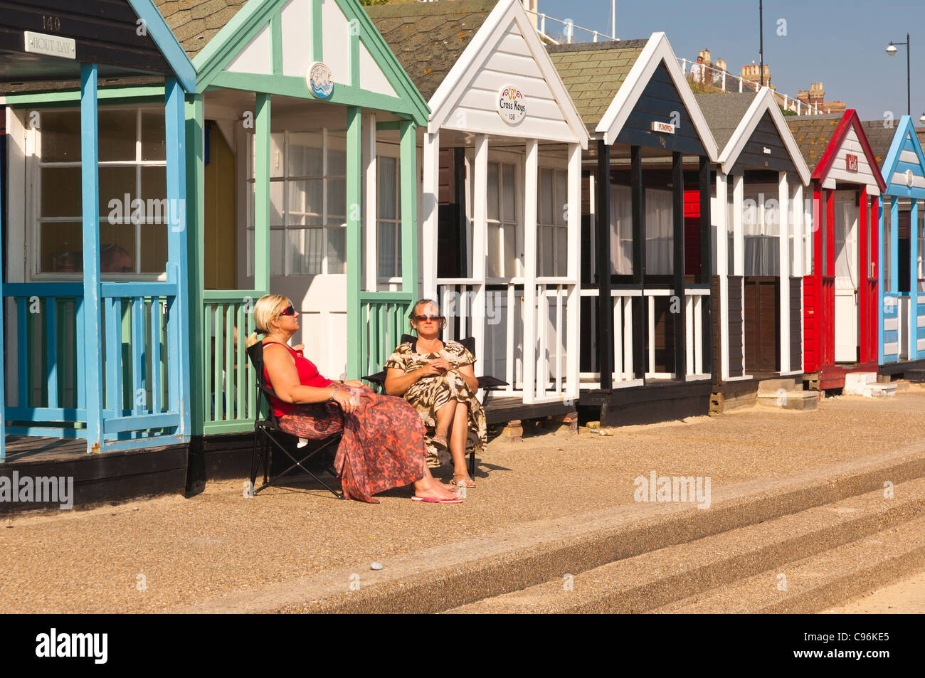 Zwei Frauen sitzen außerhalb der Strandhütten im Sommer in Southwold, Suffolk, England, Großbritannien, Uk Stockfoto