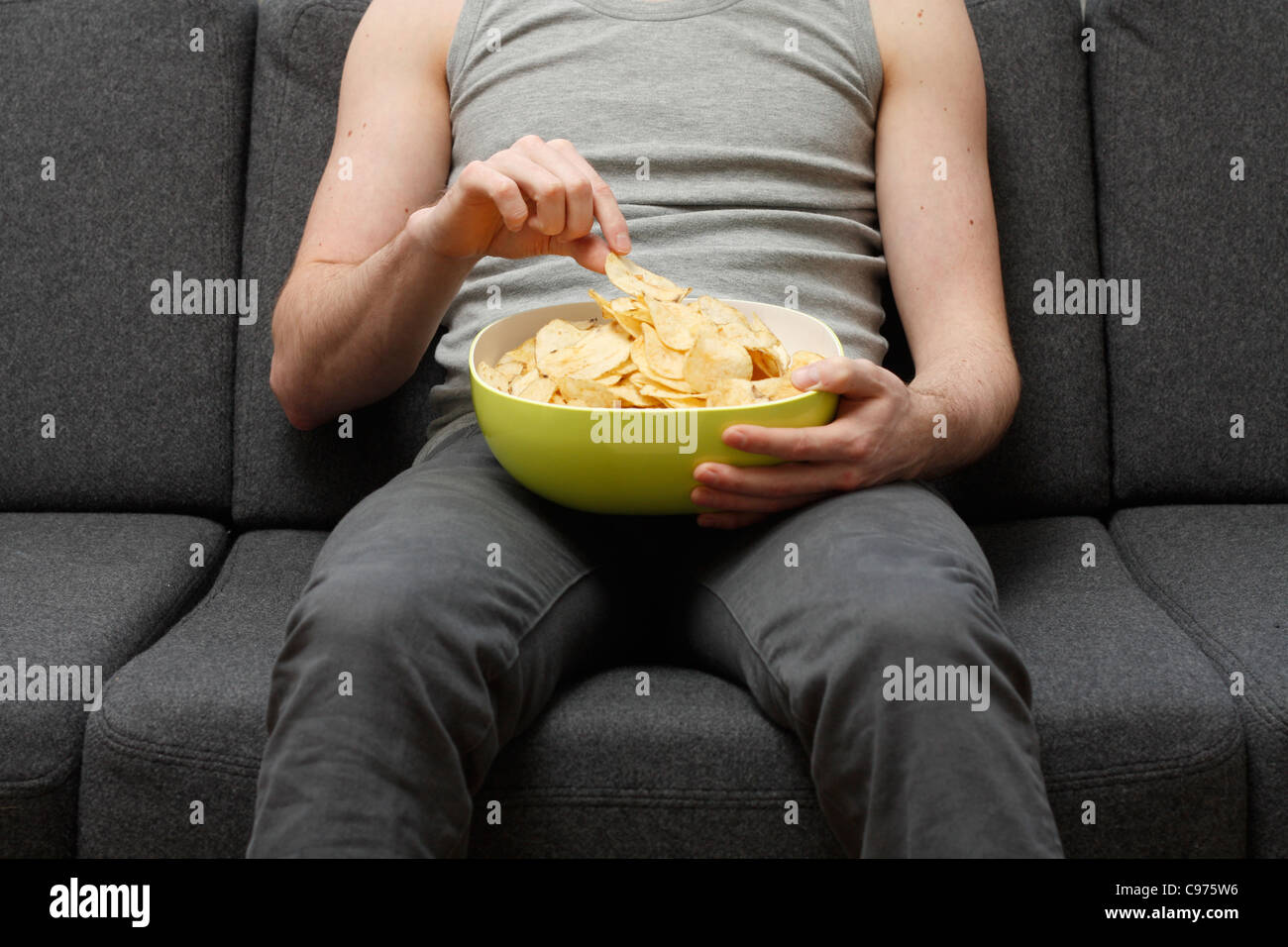 Ein Mann auf einer Couch Potato Chips Essen Stockfoto