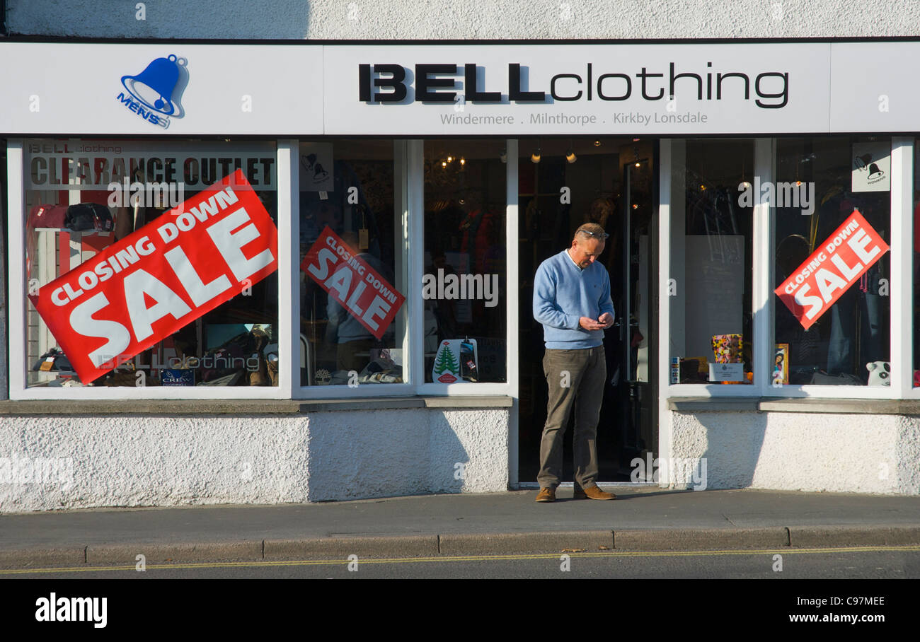Mann, der im Eingang des Shops mit Schließung Verkauf, Stadt Windermere, Lake District National Park, Cumbria, England UK Stockfoto