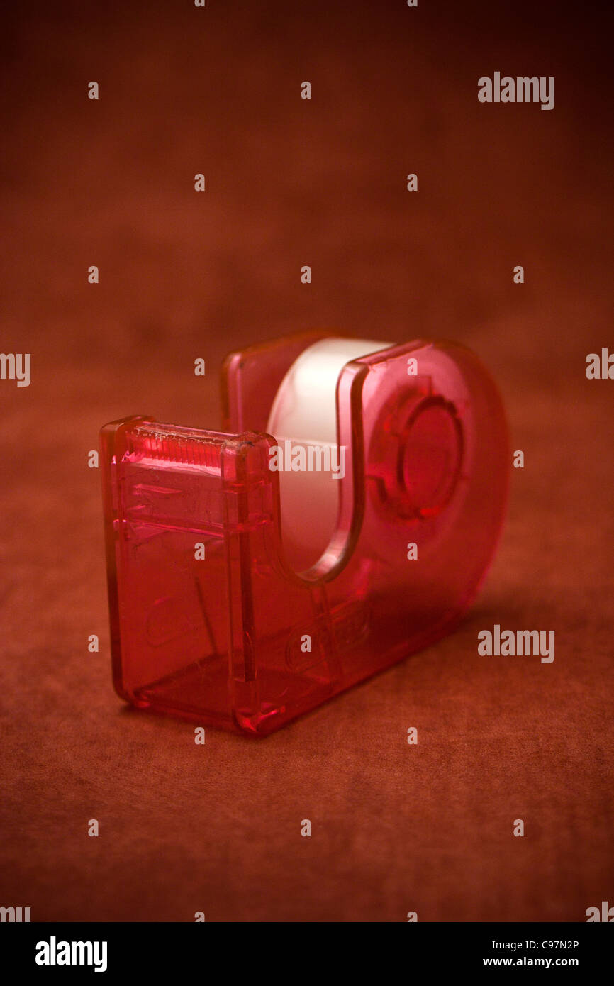rotes Klebeband und Tape-Halter vor rotem Hintergrund Stockfoto