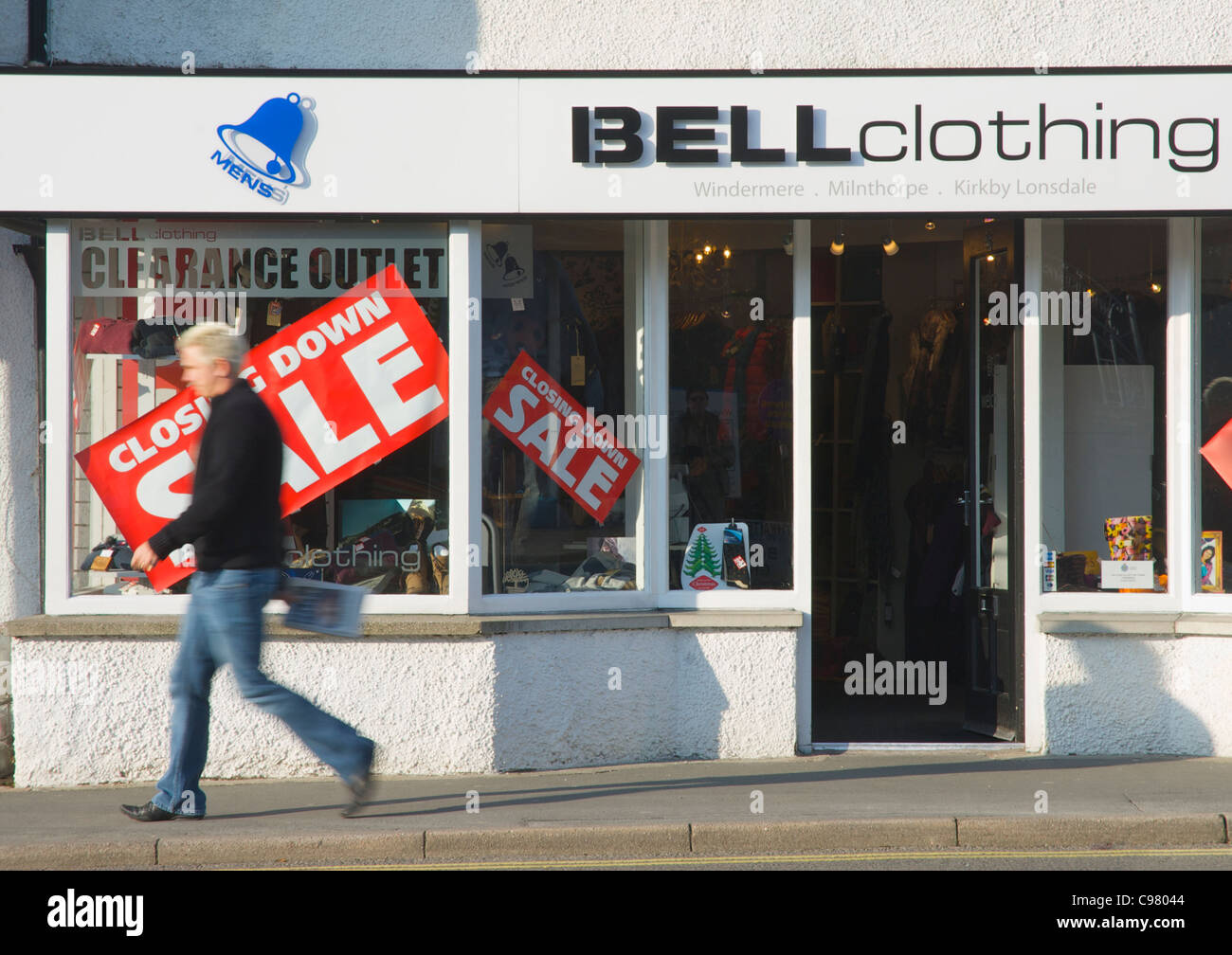 Mann zu Fuß vorbei an Shop mit Verkauf, Stadt Windermere, Lake District National Park, Cumbria, England UK Schließung Stockfoto