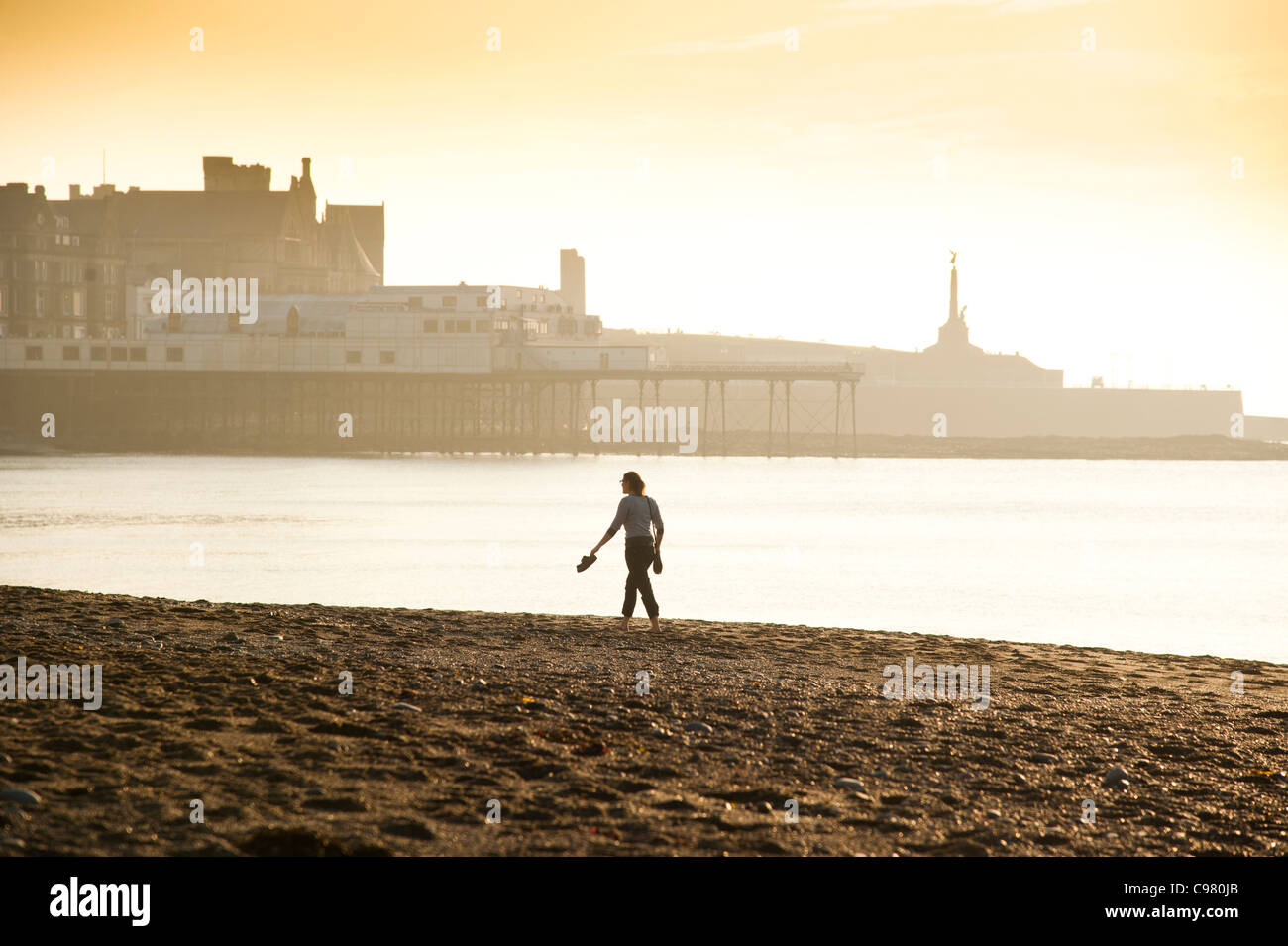 Eine Frau barfuss am Strand und genießen einen sehr warmen November Nachmittag, Aberystwyth Ceredigion Wales UK Stockfoto