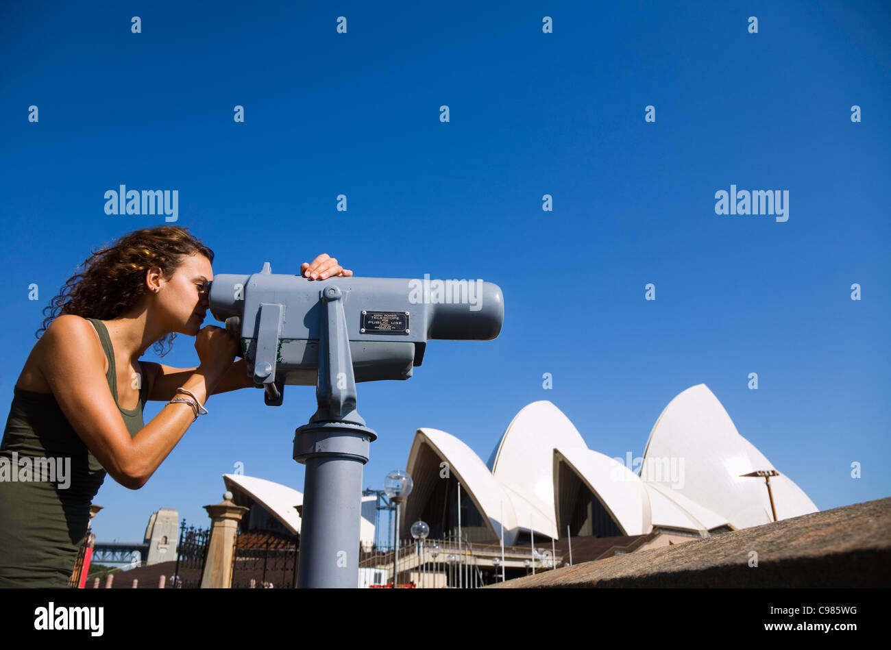 Ein Tourist schaut durch ein Teleskop mit der Oper von Sydney im Hintergrund.  Sydney, New South Wales, Australien Stockfoto