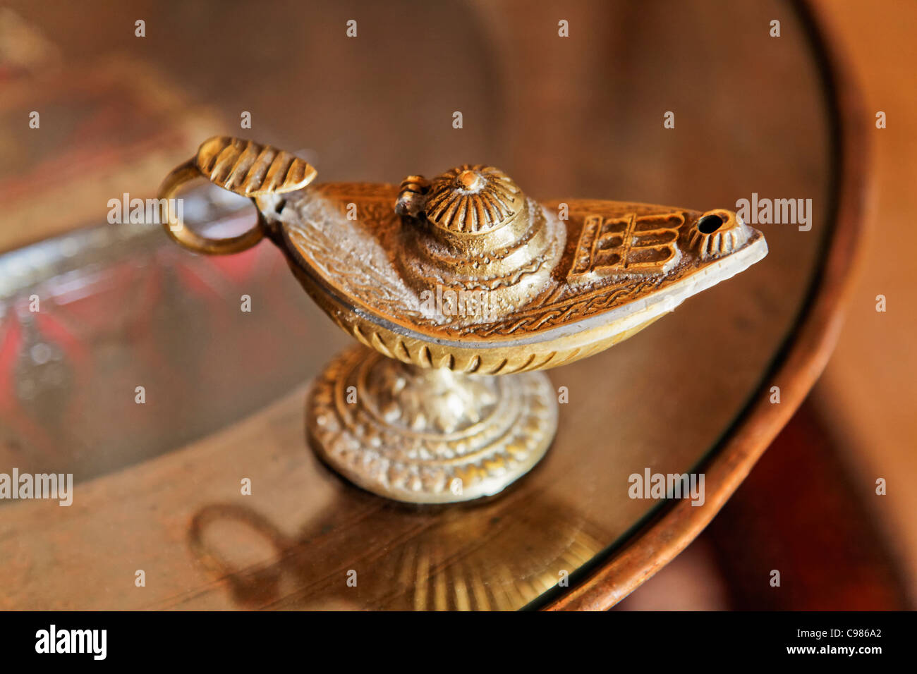 Aladdin verzierten Messing Genie Öllampe mit Griff auf eine Runde Beistelltisch Landschaft Raum zuschneiden und kopieren. Stockfoto