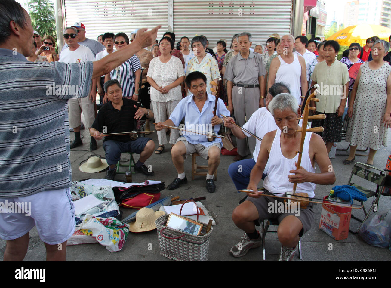 Anwohner und Musiker unter der Leitung von eine pensionierte Lehrerin unterhalten Kreuzfahrt-Passagiere mit Liedern in Fengdu, China Stockfoto