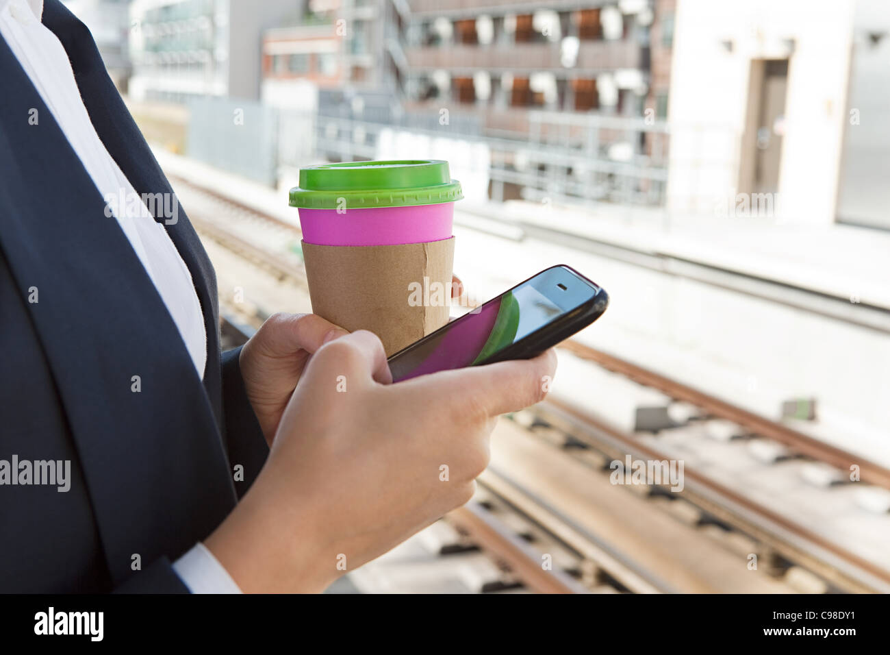 Frau mit Kaffee und Smartphone-Bahnhof hautnah Stockfoto
